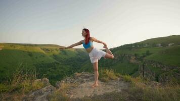 atletisk kvinna håller på med yoga poser på topp av en berg under solnedgång. sporter flicka tåg och gör stretching övningar i de berg. friska livsstil, zenism, träna begrepp. långsam rörelse. video