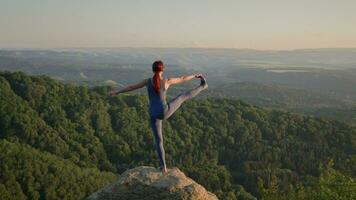 yoga session i de berg. ung atletisk kvinna utövar i de klippig bergen under soluppgång, håller på med olika yoga poser - friska livsstil och zenism begrepp. långsam rörelse. video