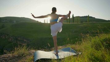 yoga session dans le montagnes. Jeune athlétique femme exercice dans le rocheux montagnes pendant lever du soleil, Faire divers yoga pose - en bonne santé mode de vie et zénisme concept. lent mouvement. video