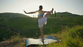 yoga sesión en el montañas. joven atlético mujer hacer ejercicio en el rocoso montañas durante amanecer, haciendo varios yoga poses - sano estilo de vida y zenismo concepto. lento movimiento. video