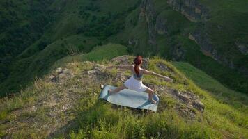 yoga sessie in de bergen. jong atletisch vrouw oefenen in de rotsachtig bergen gedurende zonsopkomst, aan het doen divers yoga poses - gezond levensstijl en zenisme concept. langzaam beweging. video
