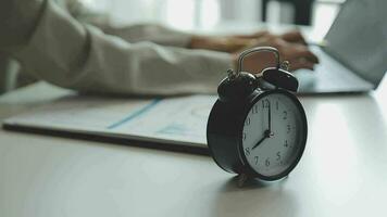 Female hand on the alarm clock a red color stands in the office on the table showing eight o'clock in the morning or evening AM PM. video