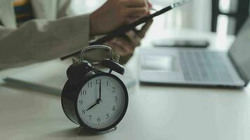 Female hand on the alarm clock a red color stands in the office on the table showing eight o'clock in the morning or evening AM PM. video