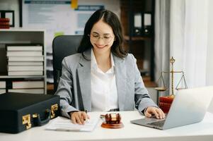 justice and law concept. Female judge in a courtroom the gavel, working with smart phone and laptop and digital tablet computer on white table photo