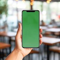 AI Generative Women hand holding smart phone with the screen is blank plain bright green, blur cafe background photo