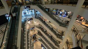 personas en escaleras mecánicas en de muchos pisos compras centro comercial foto