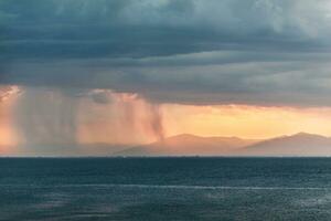 Rain clouds in distant plains near mountains photo