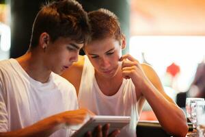 Young men searching on the internet with pad in cafe photo