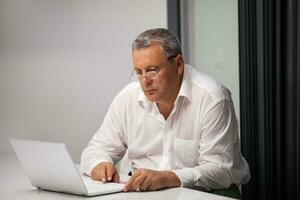 Senior businessman working with laptop in office photo