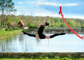 rítmico gimnasta niña hacer ejercicio con cinta al aire libre foto