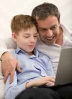 Happy dad and son with laptop at home photo