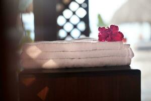 Pile of three white clean towels with flower on top photo