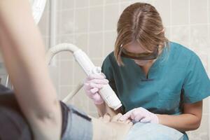 Female cosmetician doing foot therapy using laser photo