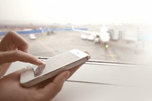 Woman using smart phone by the window at aiport photo