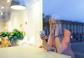 Smiling woman in cafe reading or typing sms photo