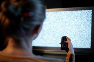 Woman with remote control in front of TV set photo