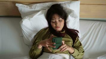 un triste joven asiático mujer es llorando terminado su teléfono mientras acostado en el cama video