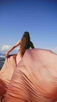 Girl in a long dress against the backdrop of the ocean in Bali. Vertical video. video