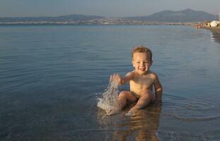 linda pequeño chico salpicaduras en el mar foto