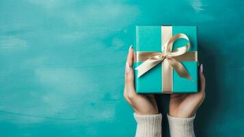 Top view of hands holding gift box with copy space on turquoise background, Generative ai. photo