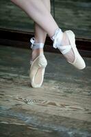 Dancing feet in ballet shoes on wooden floor photo