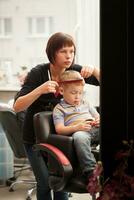 Little boy getting a haircut from hairdresser photo