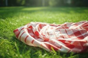 Red and white plaid picnic blanket on top of a green field in sunny day on grass of lawn in summer park. Blurred Background. Generative AI photo