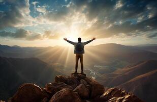 The silhouette of a tourist standing with his arms outstretched the golden glow of the morning sun on the mountaintop. Standing up to achieve success. photo