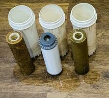 Three used water filters with traces of dirt, clay and contaminants. Replacing multi-stage water filter cartridges. photo
