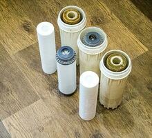 Used water filters with traces of dirt, clay and impurities and clean filters, prepared for replacement. Replacing multi-stage water filter cartridges. photo