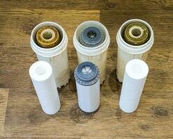 Used water filters with traces of dirt, clay and impurities and clean filters, prepared for replacement. Replacing multi-stage water filter cartridges. photo