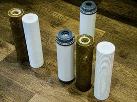 Used water filters with traces of dirt, clay and impurities and clean filters, prepared for replacement. Replacing multi-stage water filter cartridges. photo