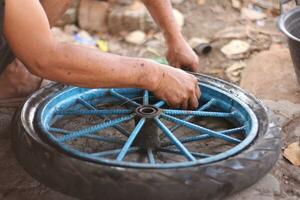 An Indonesian service worker is changing the tire of a bicycle cart manually photo