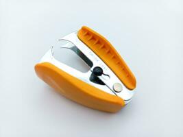 Orange Staple Remover Isolated On White Background. Tilted View From Above photo