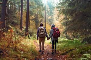 Back view of a young couple with backpacks walking through the forest. photo