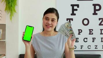 mulher segurando telefone com dinheiro dólar contas, o negócio e finança conceito, segurando telefone verde tela video