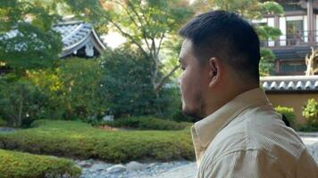 asian man enjoy relaxing breathe in japanese zen style garden in autumn daytime, relax peaceful video