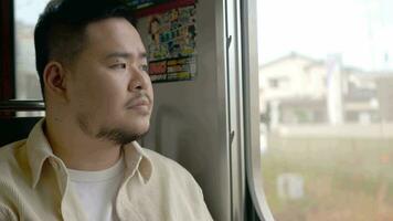 asian man travel with local train relaxing near window while train moving in daytime video