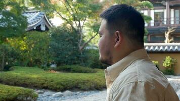 asiatique homme prendre plaisir relaxant respirer dans Japonais Zen style jardin dans l'automne jour, se détendre paisible video