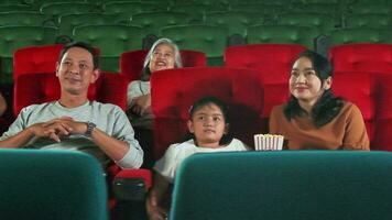 asiatico famiglia pubblico gode Guardando cinema insieme a film teatri. ragazzo e genitori avere interno divertimento stile di vita con prestazione arte Spettacoli, contento e allegro con Popcorn e un' Sorridi. video