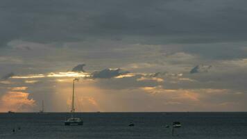 Golden rays of the sun through the cloudy. Seascape, timelapse. Yachts floating near the shore. Tourism and travel concept video