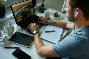 Man sitting at table by the window and using laptop photo