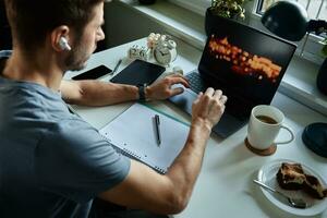 Man sitting at table by the window and using laptop photo