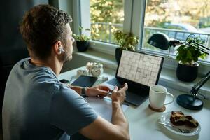 Man sitting at table by the window and using laptop photo