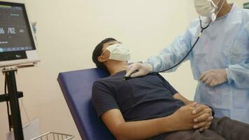 The doctor checks the patient's respiratory rate or pulse rate by using a stethoscope Asian man patients are checked for their health while a woman doctor uses a stethoscope to hear the heart rate. video