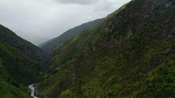 Panoramic aerial view of summer mountain valley landscape with green forest, mountain river and sky with clouds video