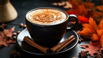 A cozy black mug filled with steaming pumpkin spice latte cinnamon sticks and fall leaves scattered around photo