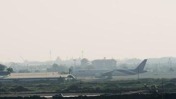 BANGKOK, THAILAND JANUARY 21, 2023 - Wide body airplane Boeing 777 of Thai Airways takeoff at Suvarnabhumi Airport. Aircraft flies in haze and backlight. Huge airliner climb, long shot video