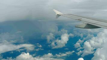 Wing of an airplane flying above the clouds on blue sky. View from a window of the plane. Concept of travelling on holidays. Landscape of aerospace. Voyage on airliner at sunny warm day. Journey trip. video