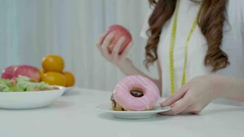 dieta y dieta. belleza cuerpo femenino delgado confundir donut. mujer con ropa de ejercicio logra el objetivo de pérdida de peso para una vida saludable, loca por la delgadez, cintura delgada, nutricionista. video